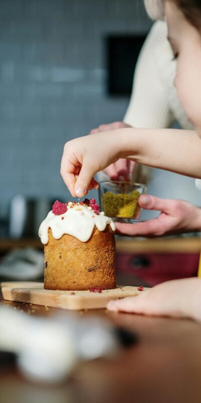 A mother and daughter bond while decorating an Easter cake in a cozy kitchen setting.