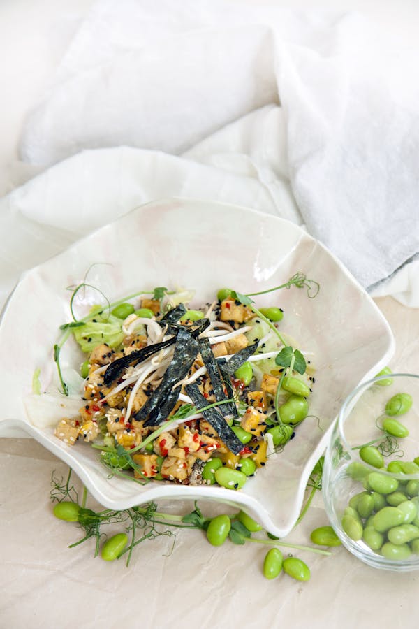 A vibrant vegetarian salad featuring edamame, quinoa, and fresh vegetables, artfully presented.