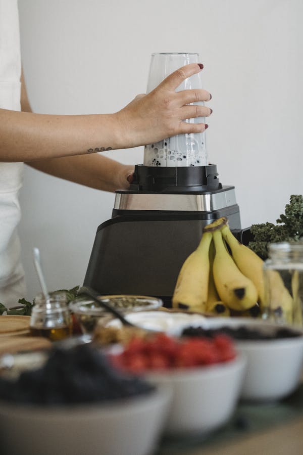 A woman using a blender to prepare a nutritious fruit smoothie with fresh ingredients.