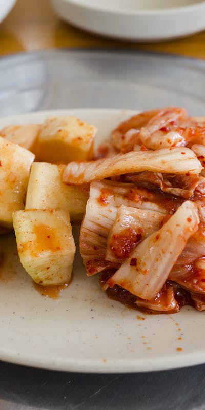 Close-up of traditional Korean kimchi and cubed radish on a plate, capturing vibrant colors and textures.