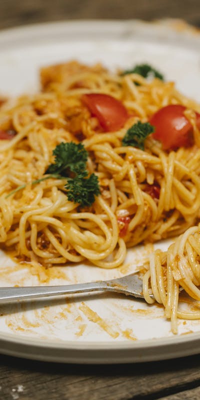 Freshly cooked spaghetti with tomatoes and parsley on a rustic table setting, inviting and appetizing.