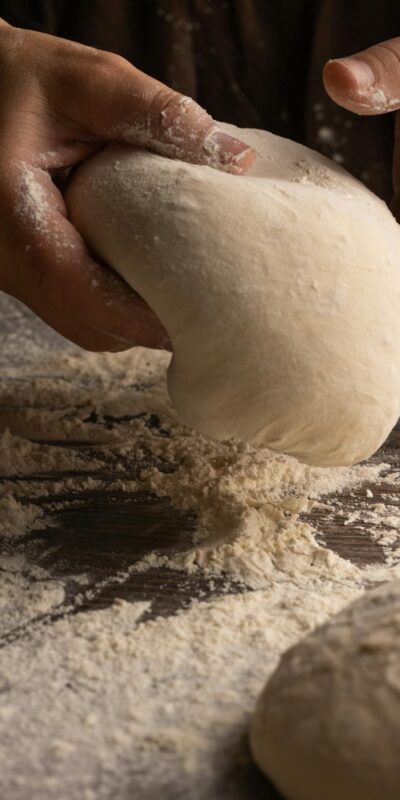 Hands kneading dough on a floured surface, capturing artisan bread making.