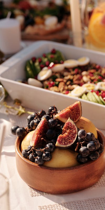 High angle of ceramic plate with fresh fruits and berries on table with various snacks