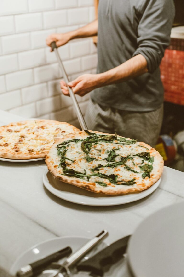 Professional pizzaiolo prepares traditional pizzas in a cozy Italian restaurant.