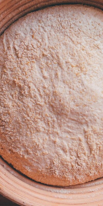 Top view of sourdough dough resting in a ceramic bowl on a wooden surface.