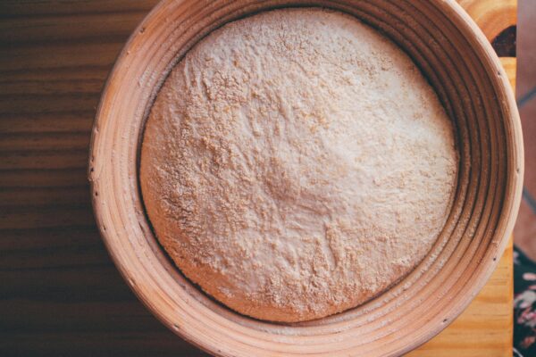 Top view of sourdough dough resting in a ceramic bowl on a wooden surface.