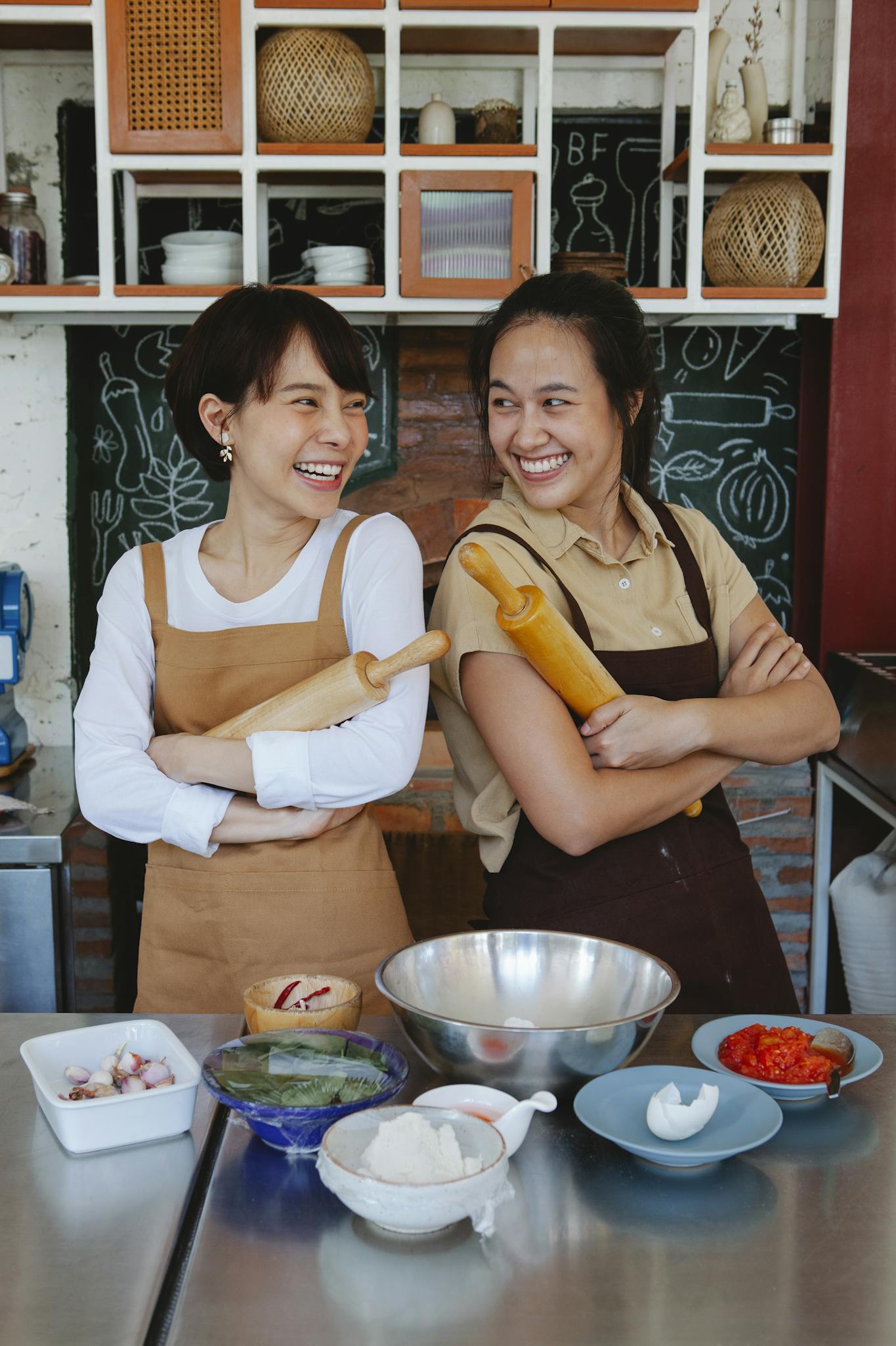 Two women smiling while preparing ingredients in a cozy kitchen setting.
